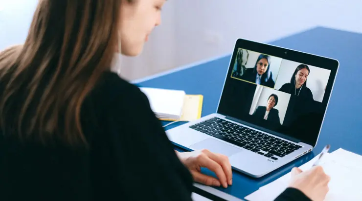 A woman is using a laptop to do a video conference.