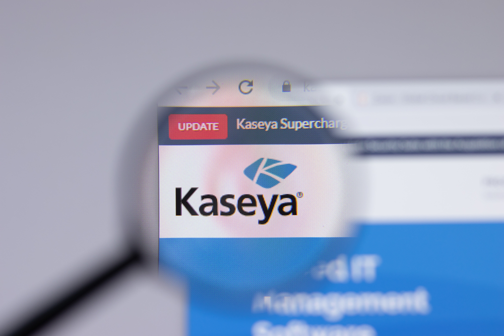 Magnified view of the kaseya logo on a computer screen under a magnifying glass, focusing on the "update" tab in a browser.