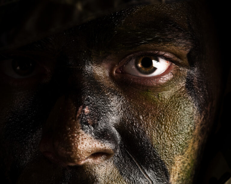 Young soldier face with jungle camouflage paint