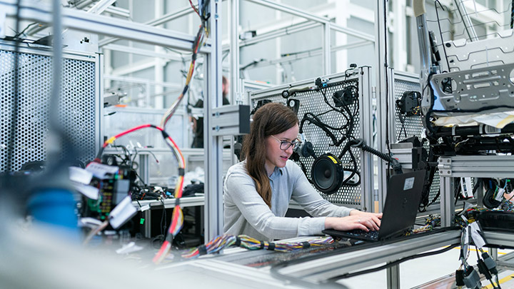 A woman utilizing cmc threat intelligence on a laptop in a factory