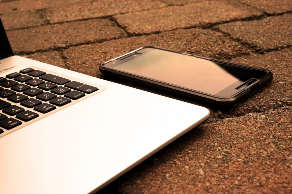 A laptop and a cell phone on a brick walkway.