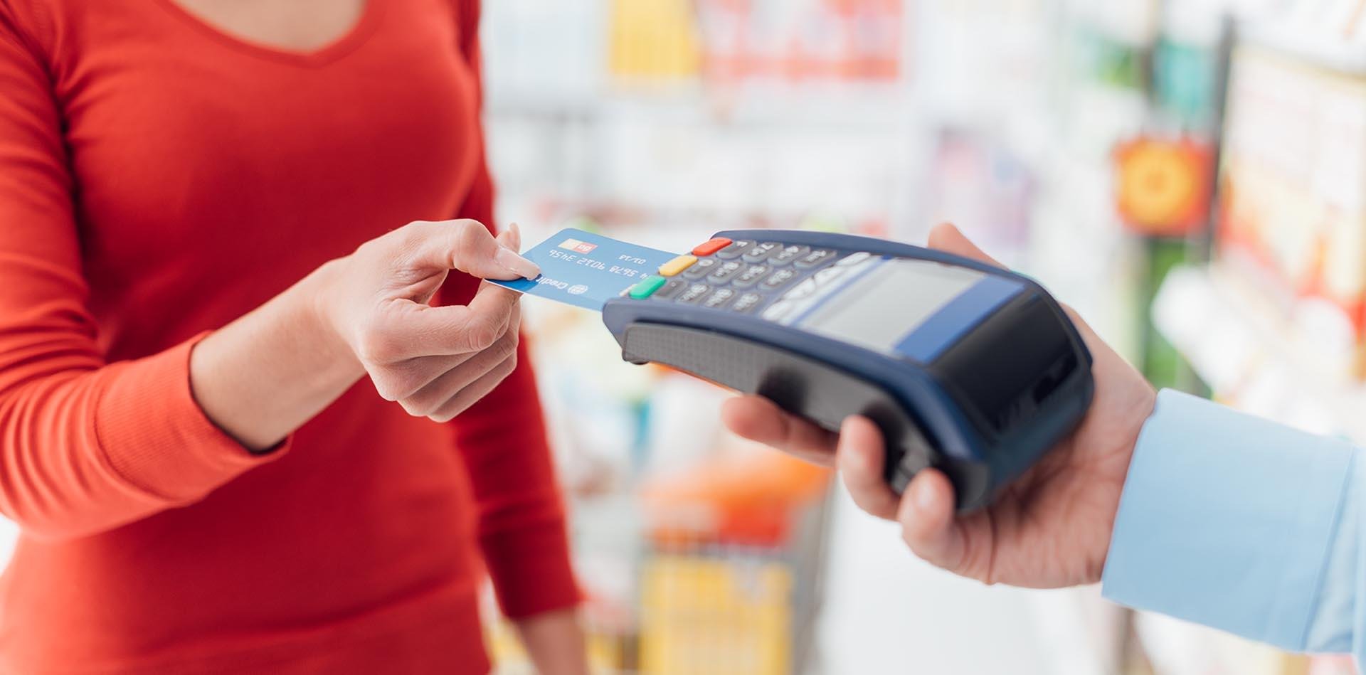 A customer is completing a purchase with her credit card. She confidently hands over her card to the merchant, assured of the pci compliance requirements that protect her credit card transactions. The secure payment environment, maintained by the adherence to the 12 pci compliance requirements set by the pci security standards council, guarantees the safe handling of her sensitive credit card information. The merchant is pci compliant, following the pci standard meticulously to ensure the customer's trust and security. This image perfectly encapsulates the importance of PCI DSS Compliance in every credit card transaction within the payment card industry.