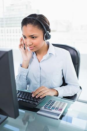 A woman wearing headphones in front of a computer.