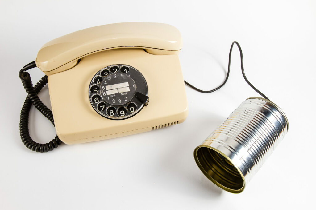 An old telephone with a tin can for a business phone system upgrade on a white background.