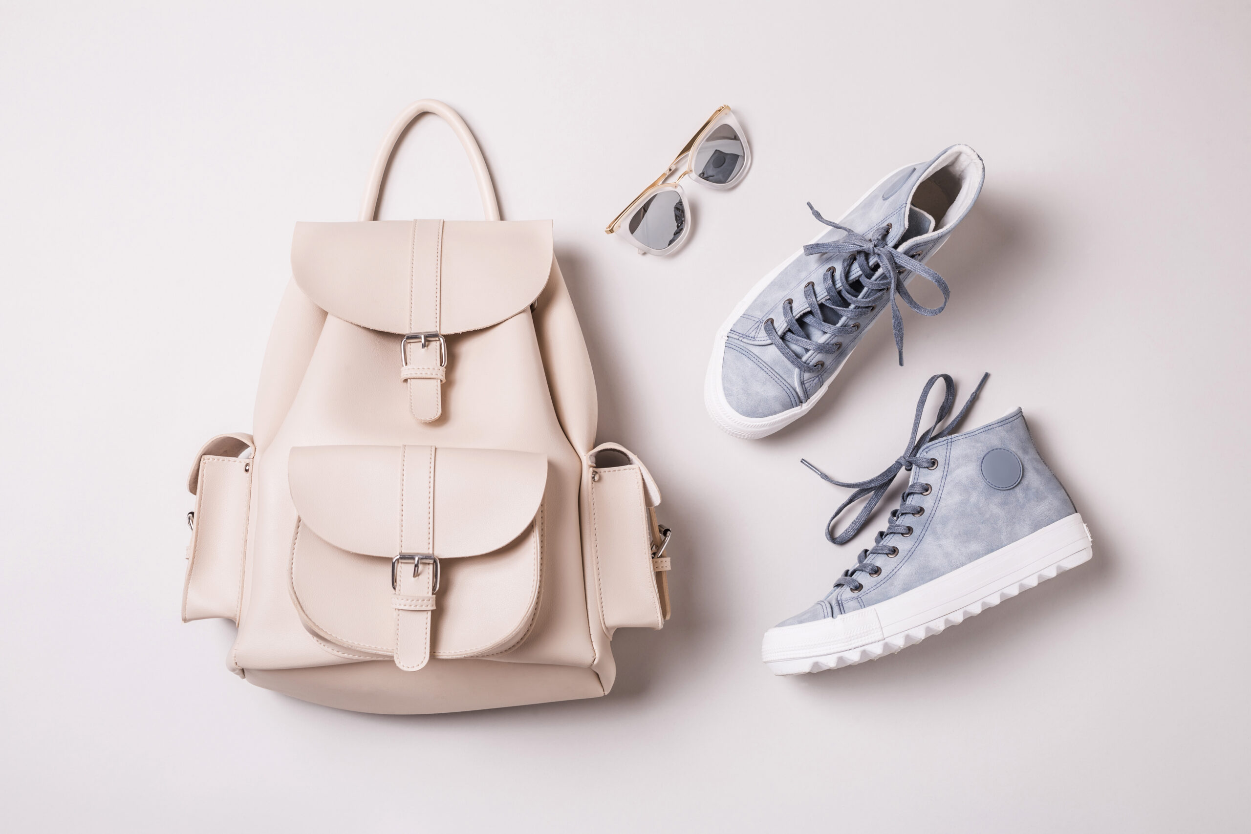 A backpack, sneakers and sunglasses on a white background, showcasing summer essentials.